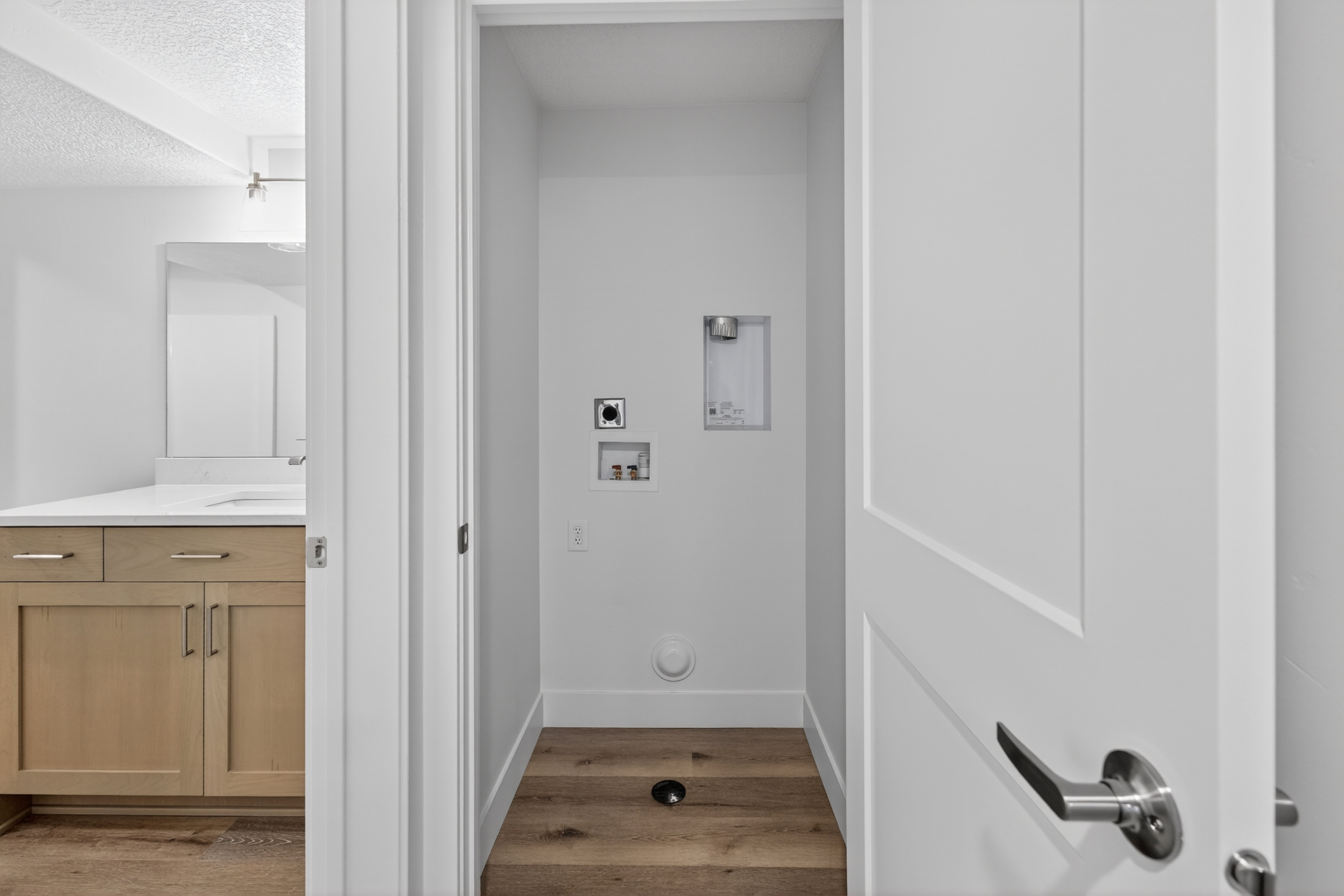 Dedicated laundry utility space with wood-finish flooring and essential hookups