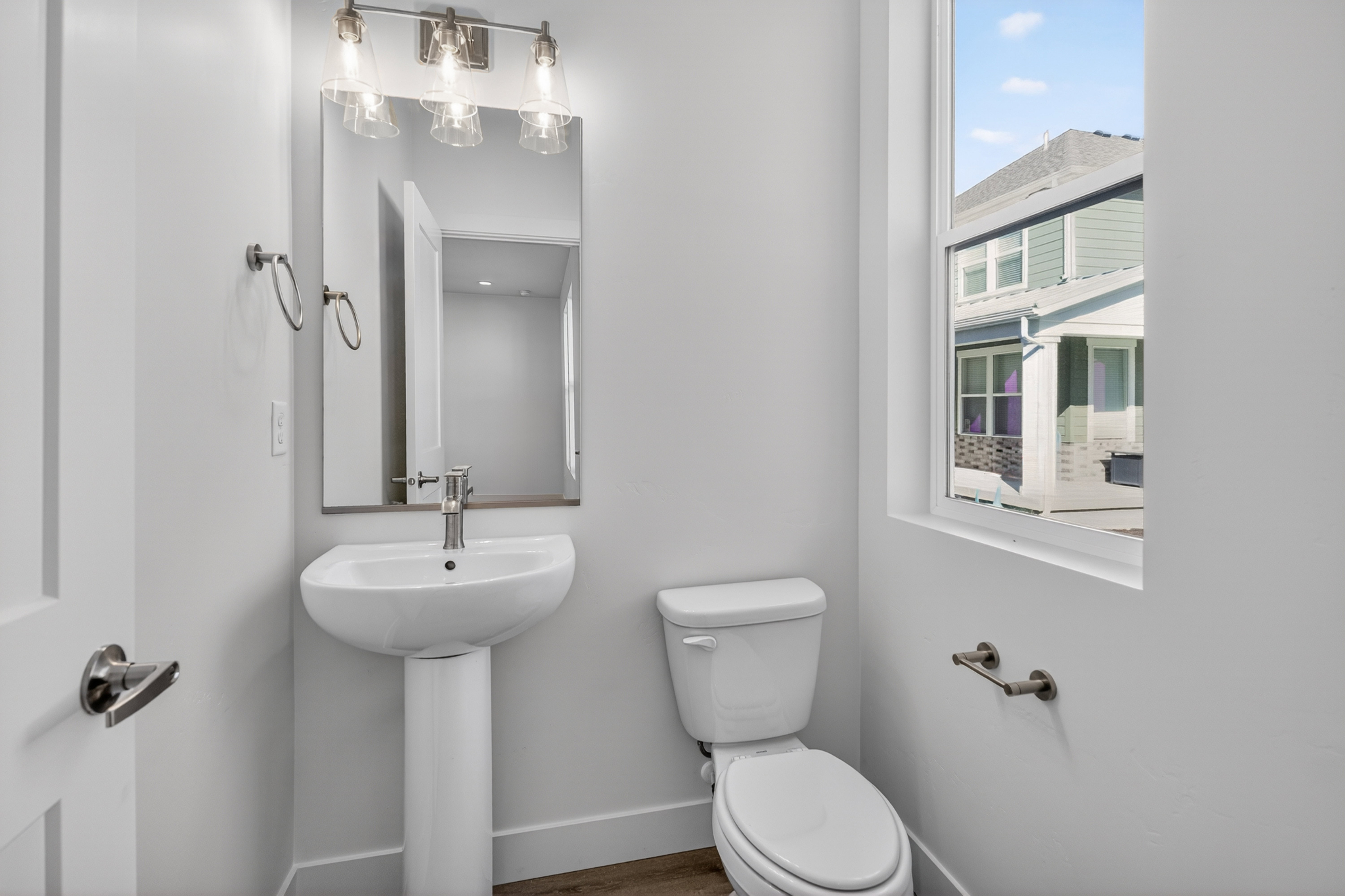 Contemporary powder room featuring a pedestal sink with a single-handle faucet, a rectangular mirror, and a three-light vanity fixture