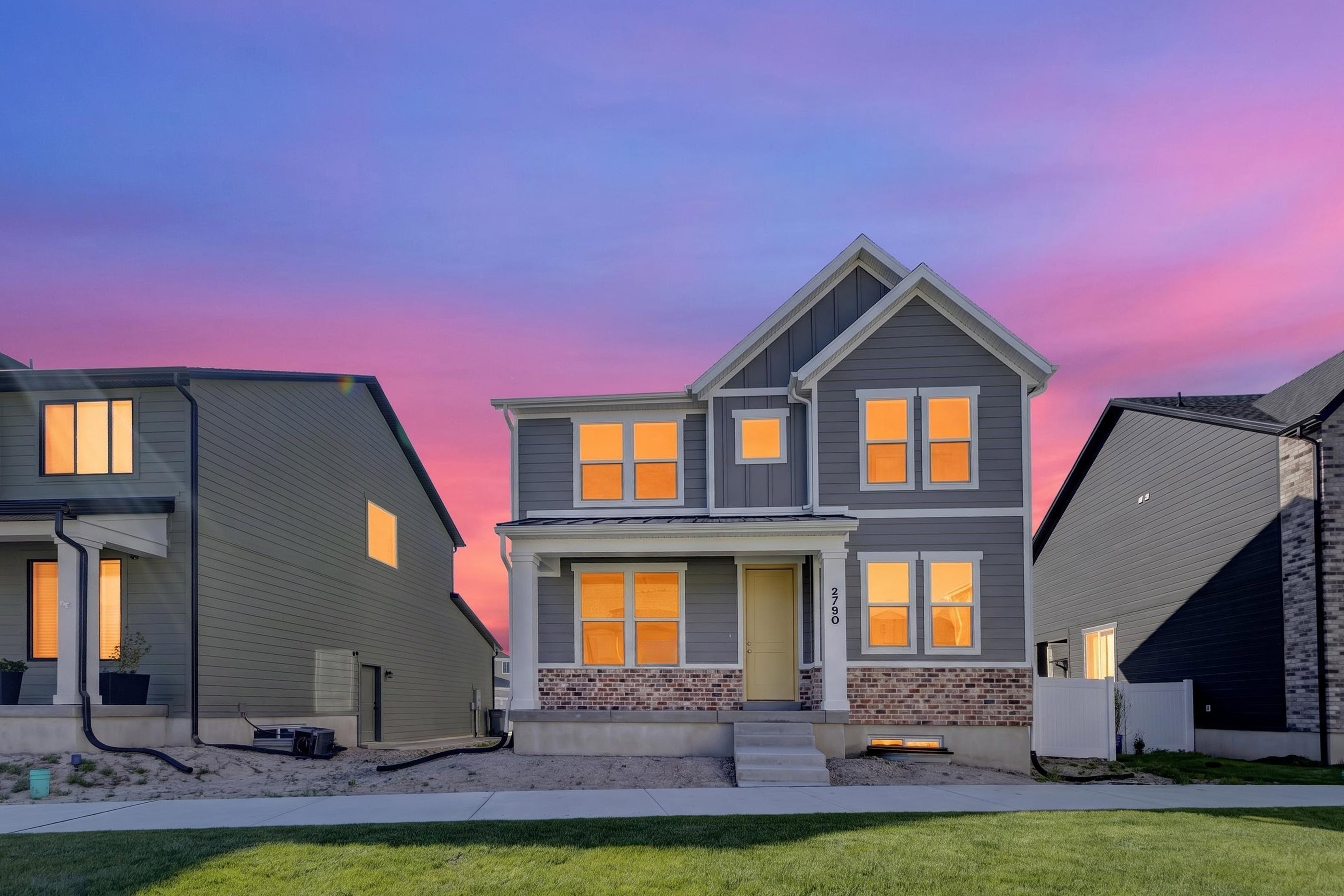 Two-story residence featuring grey siding with white trim accents and a partial brick facade