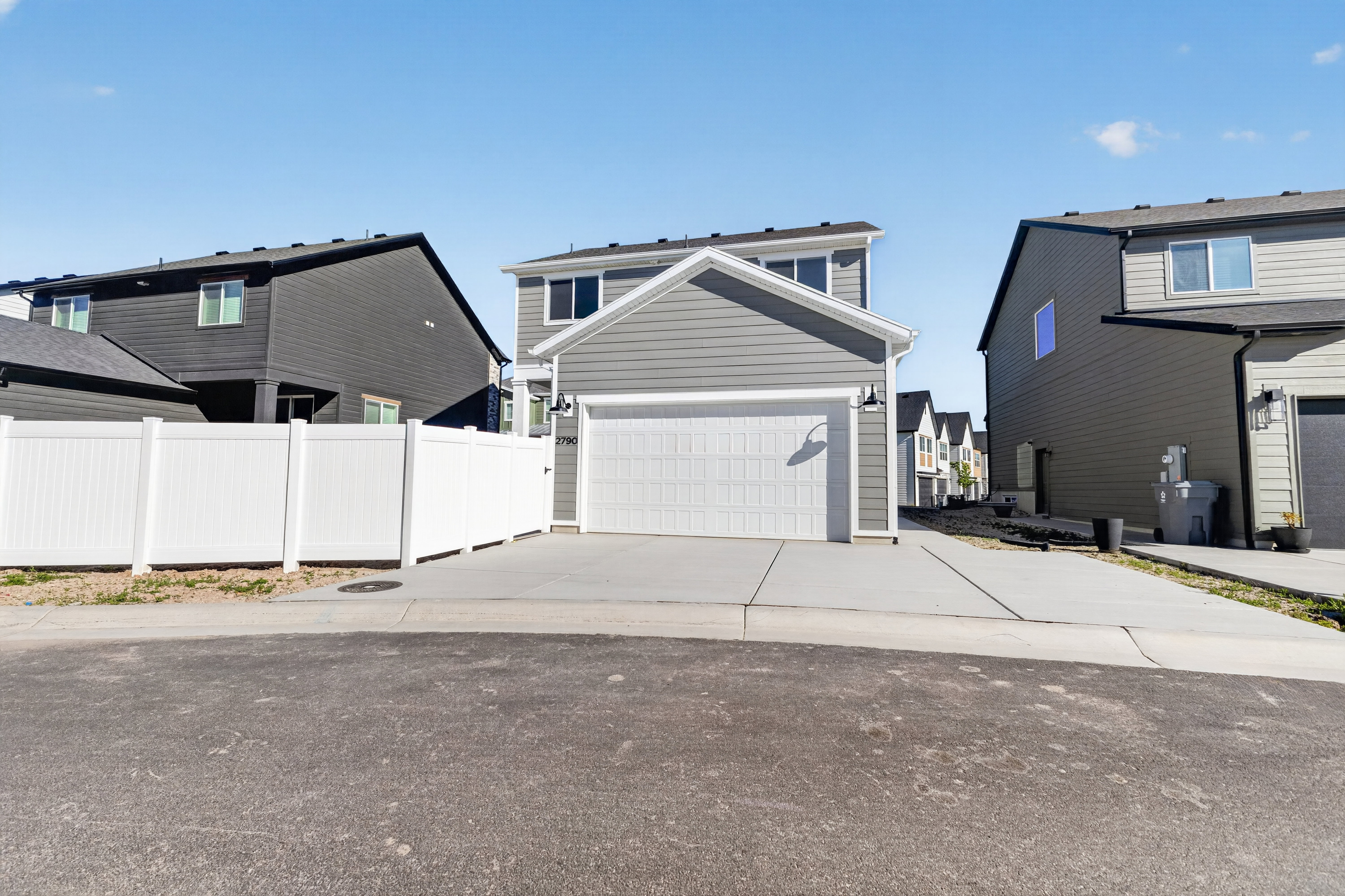 Contemporary two-story residence featuring light gray siding and a prominent attached two-car garage