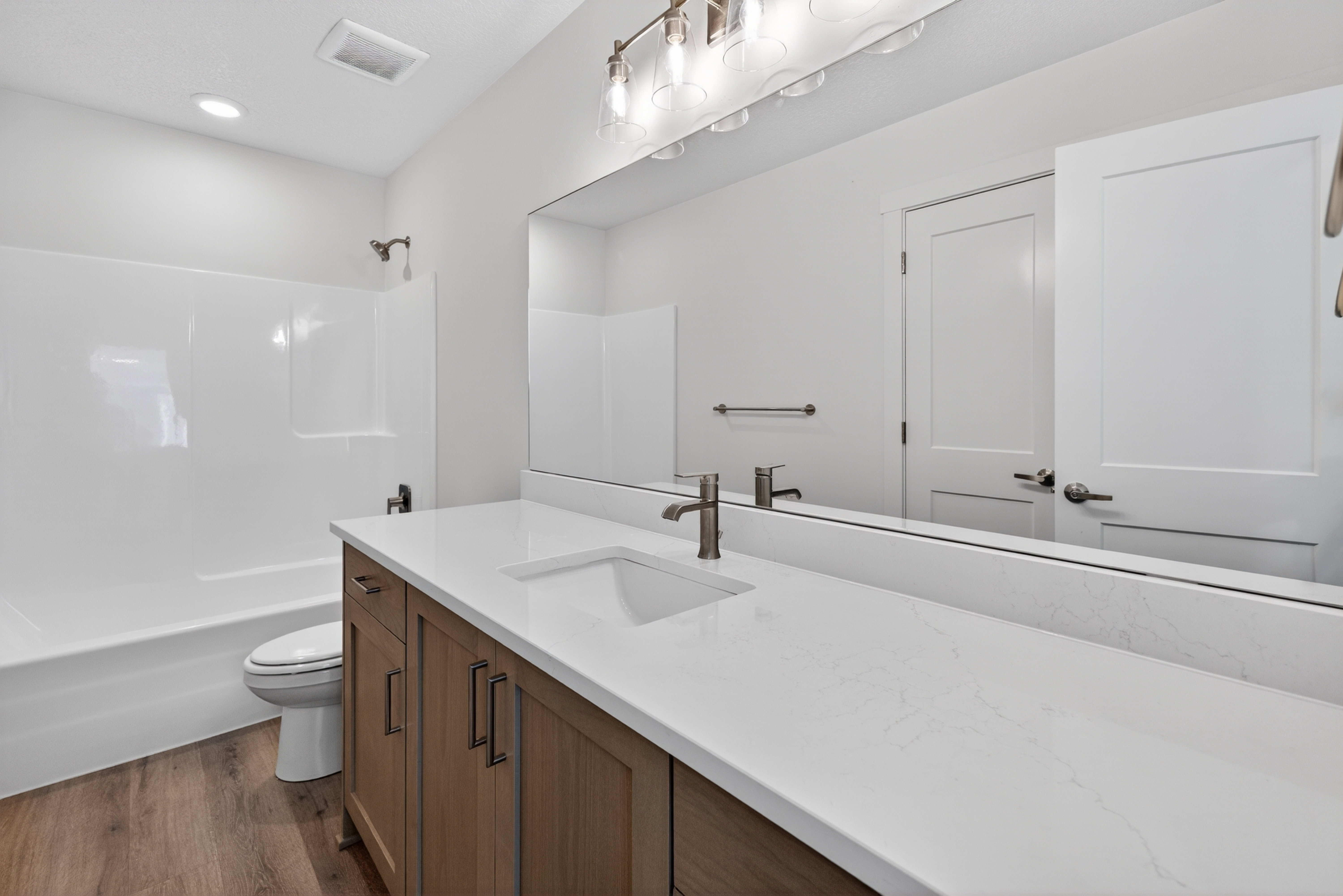 Spacious vanity featuring a light-toned countertop with integrated sink, wood-finish cabinetry, and brushed nickel fixtures