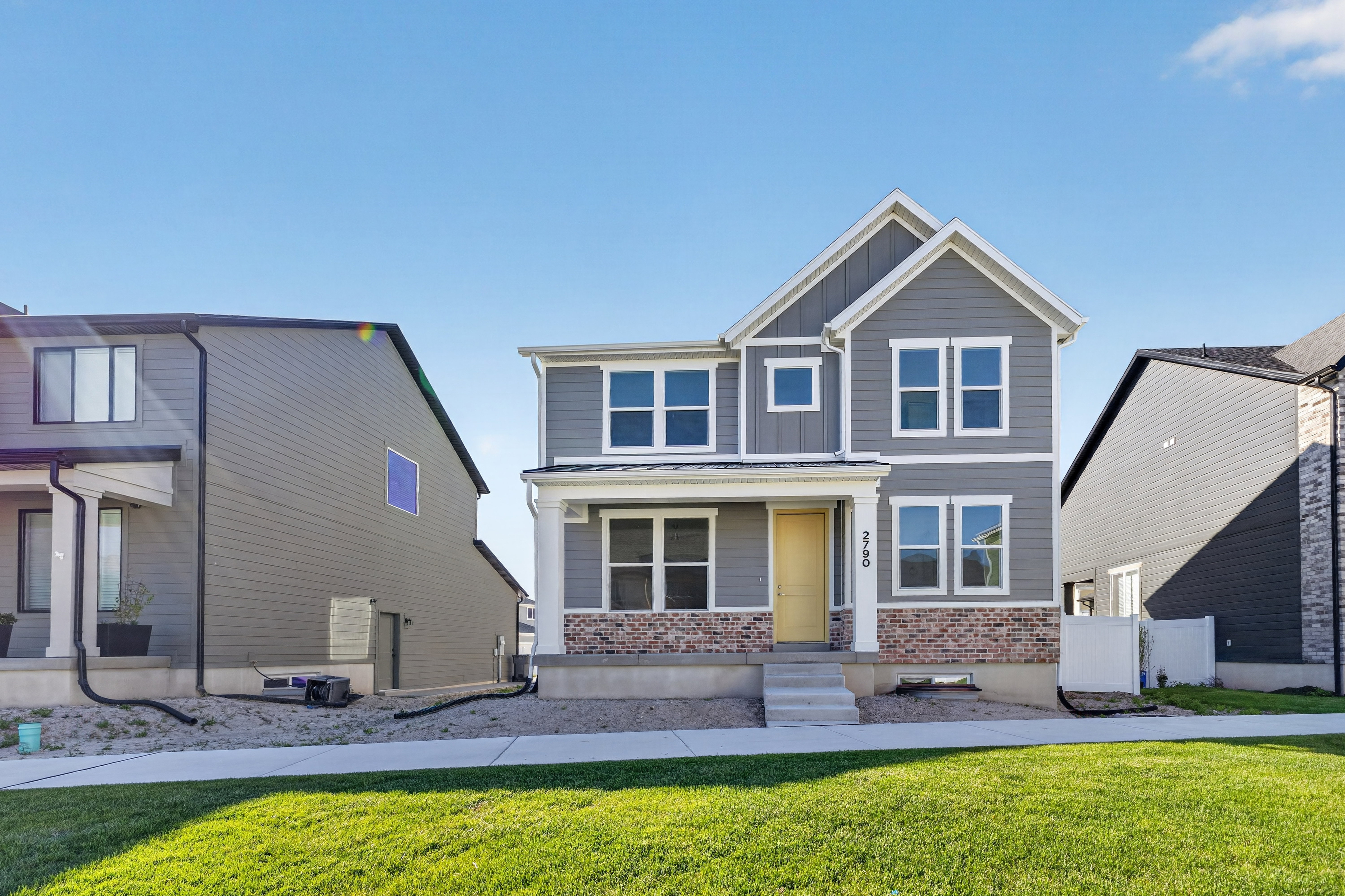 Two-story residence featuring a gray siding exterior with white trim accents and a contrasting brick facade