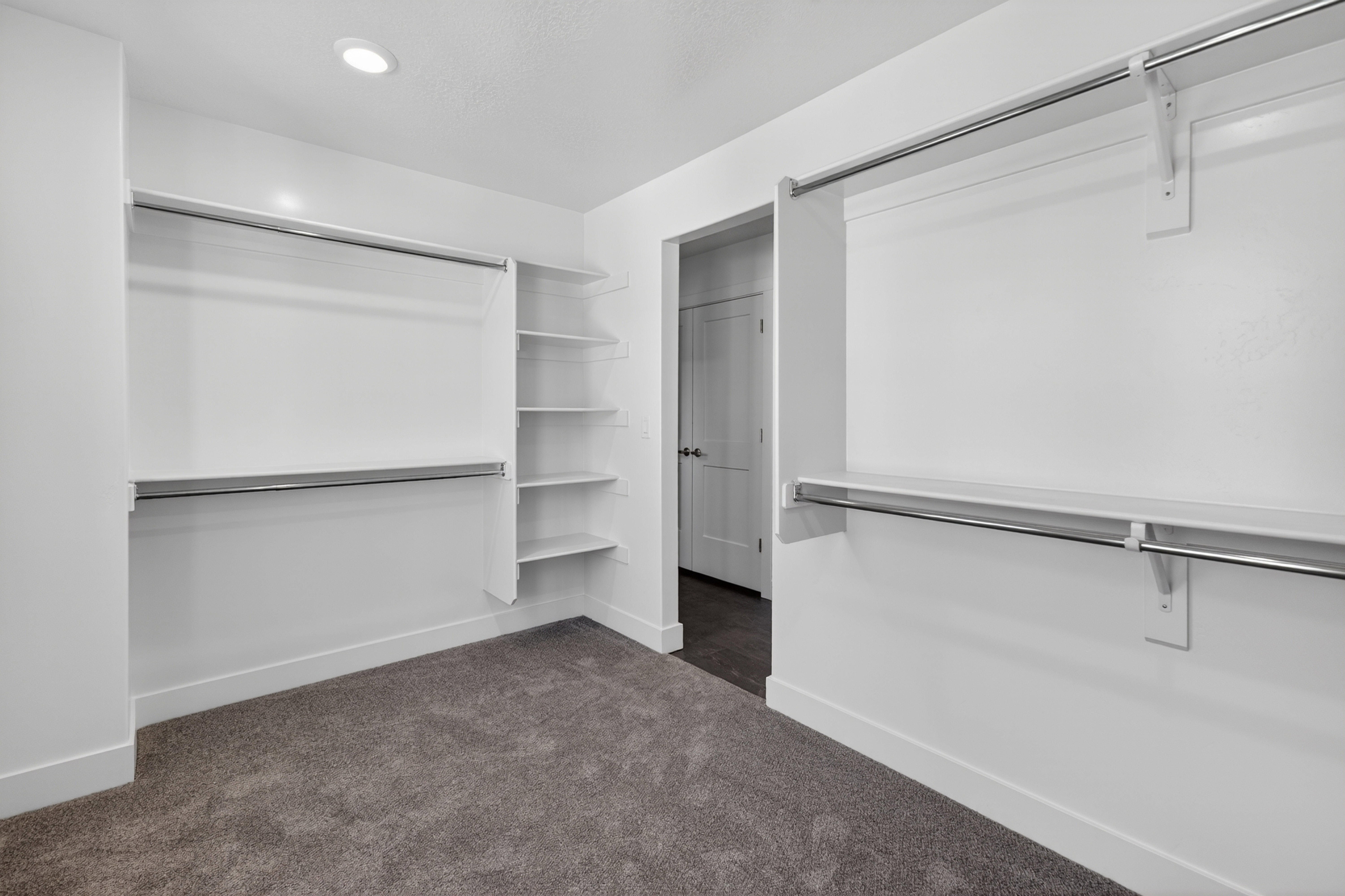 Walk-in closet featuring built-in shelving, dual hanging rods, recessed ceiling lighting, and plush carpeting