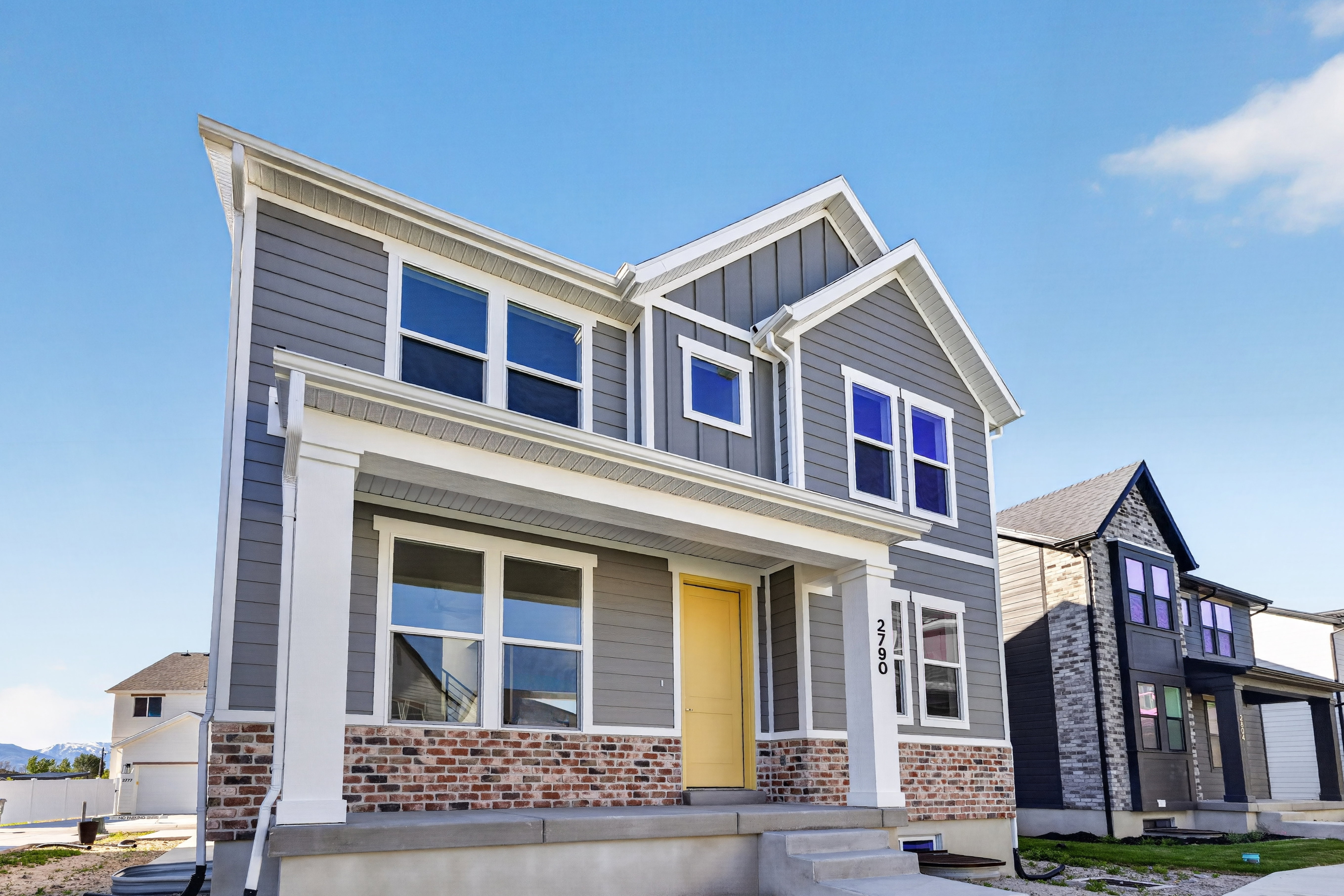 Modern two-story residence featuring grey horizontal siding and red brick accents