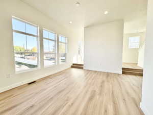 Spacious living area featuring large windows, wood-finish flooring, recessed lighting, and crisp white walls