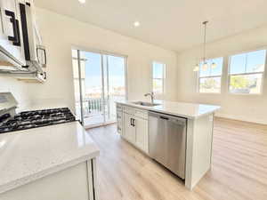 Open-concept kitchen featuring white cabinetry, quartz countertops, a gas range, and a stainless steel dishwasher
