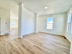 Spacious room featuring wood-finish flooring, white baseboards, and neutral wall paint