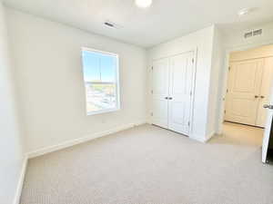 Neutral-toned carpet flooring and white walls define this space, featuring a double-pane window, two white bi-fold closet doors, and a recessed ceiling light fixture