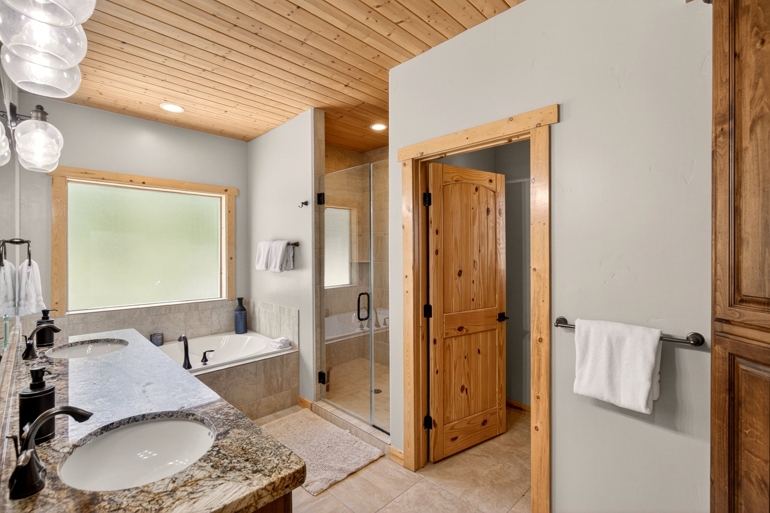 Dual vanity with granite-finish countertop and undermount sinks, alongside a jetted soaking tub