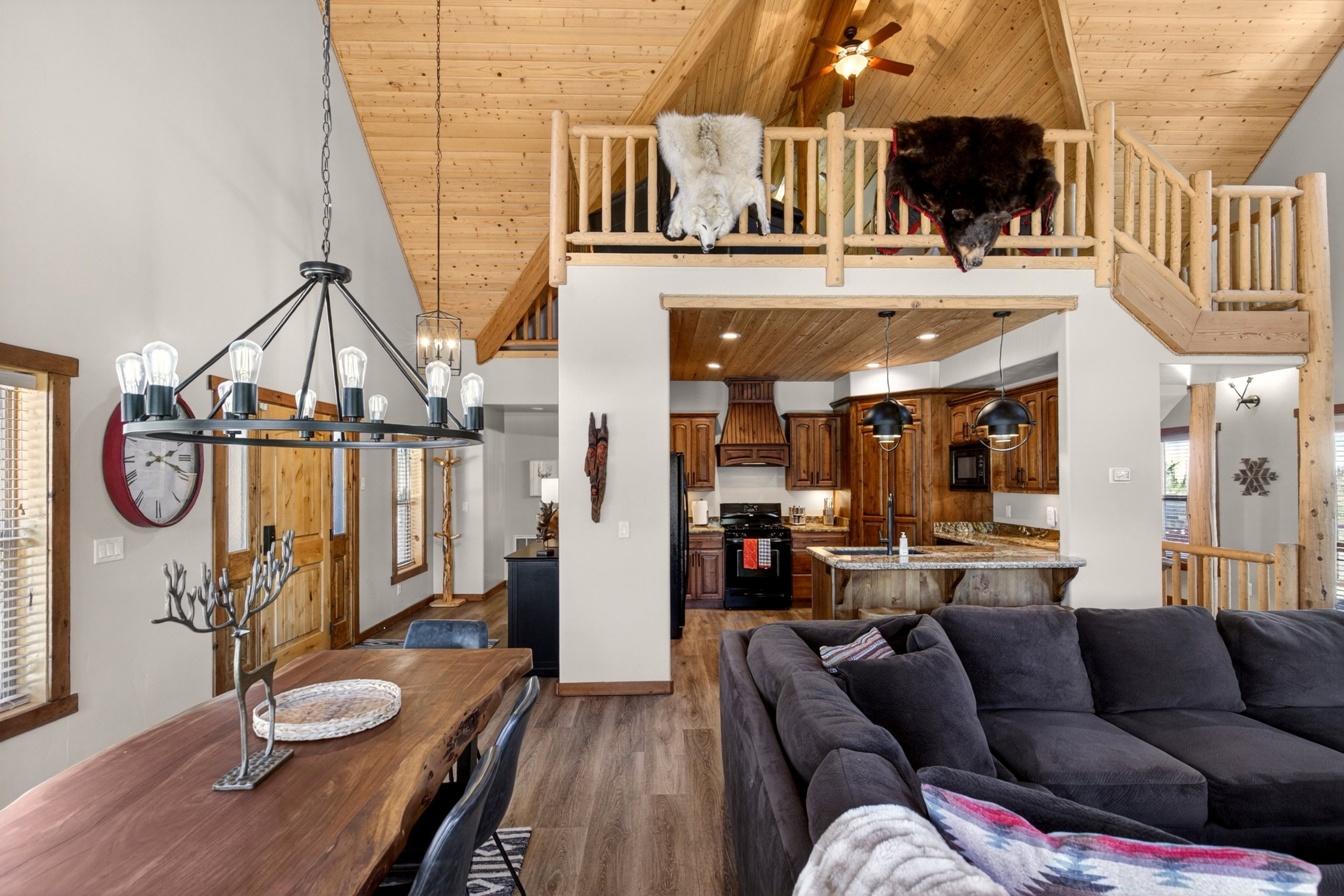 Vaulted wood-paneled ceilings with exposed beams, wood-finish flooring, and a lofted area with log railing