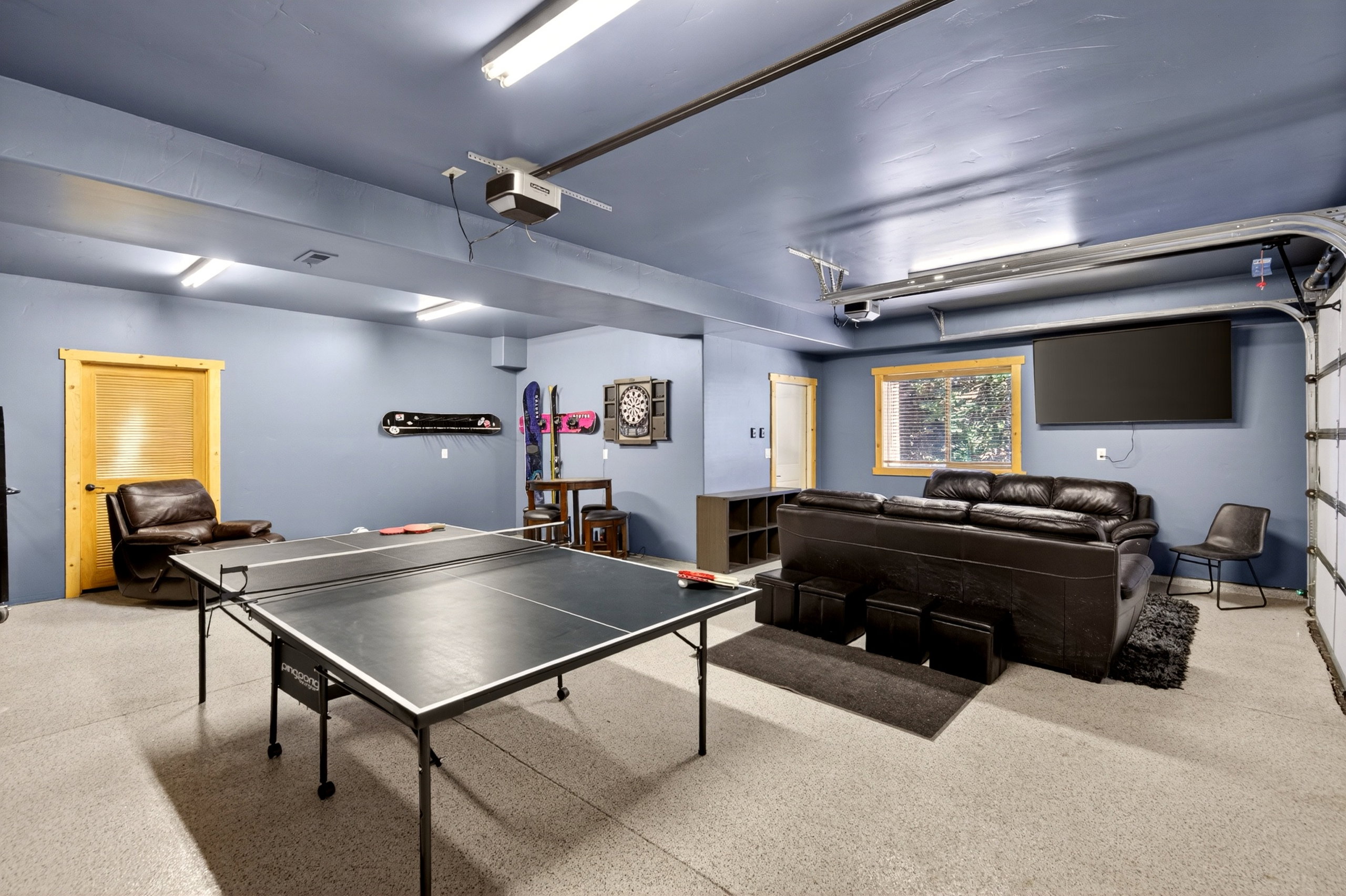 Spacious multi-purpose room featuring a light-colored epoxy floor, recessed lighting, and a large window with natural wood trim