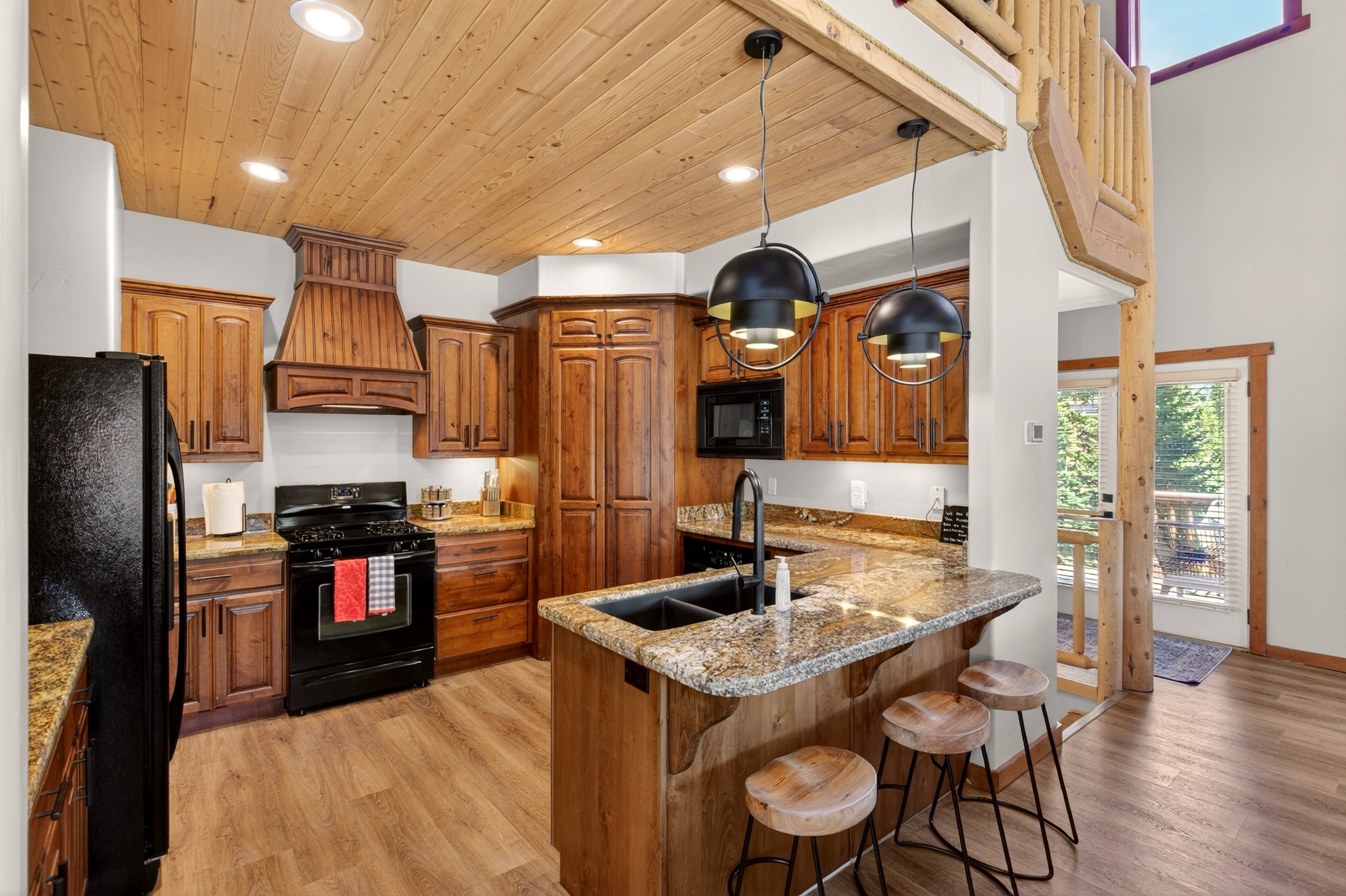 Well-appointed kitchen featuring wood-finish cabinetry, granite countertops, and a wood-planked ceiling