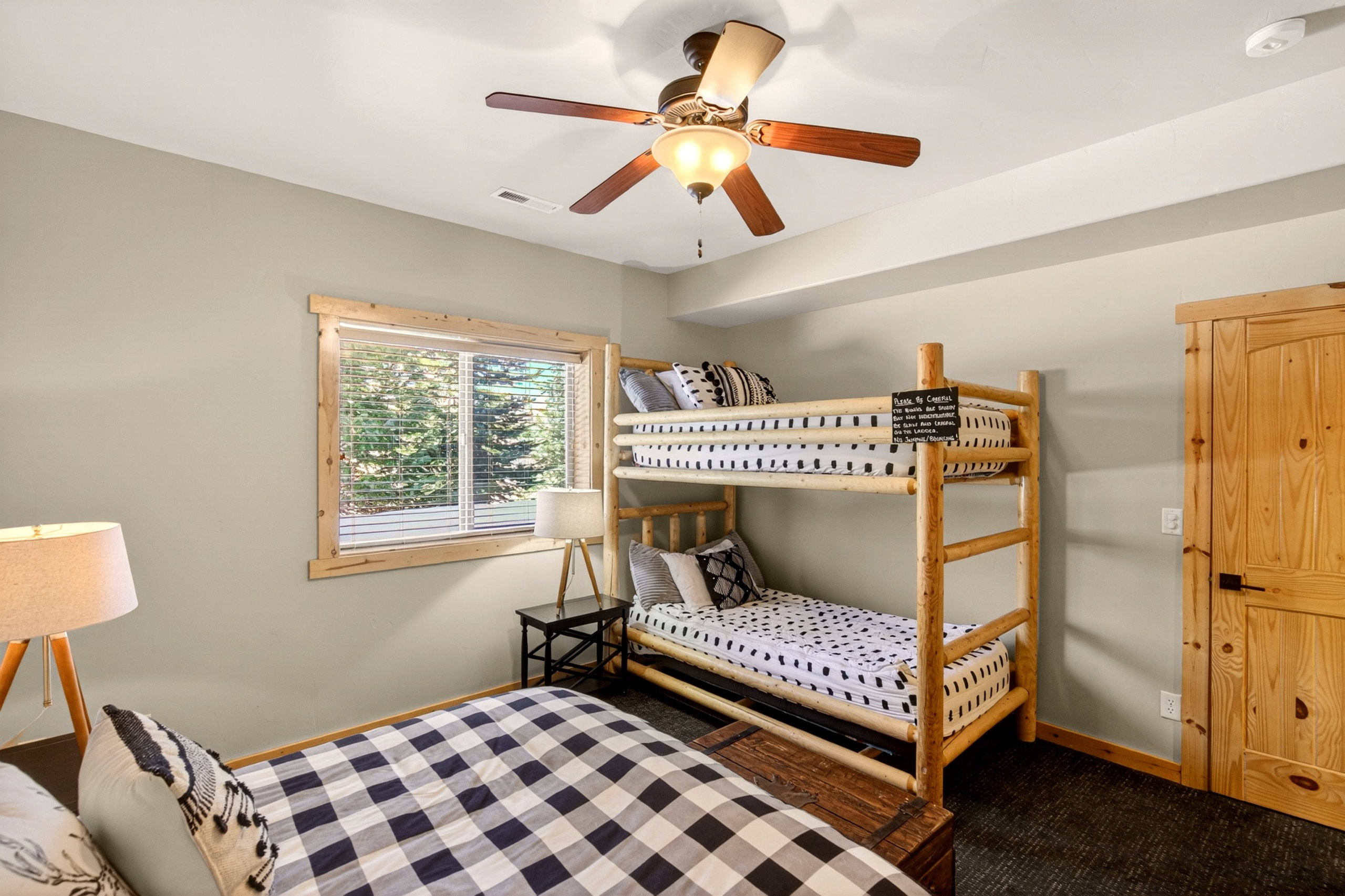 Wood-framed window with blinds, wood-finish flooring, wood-paneled door, and ceiling fan with lighting