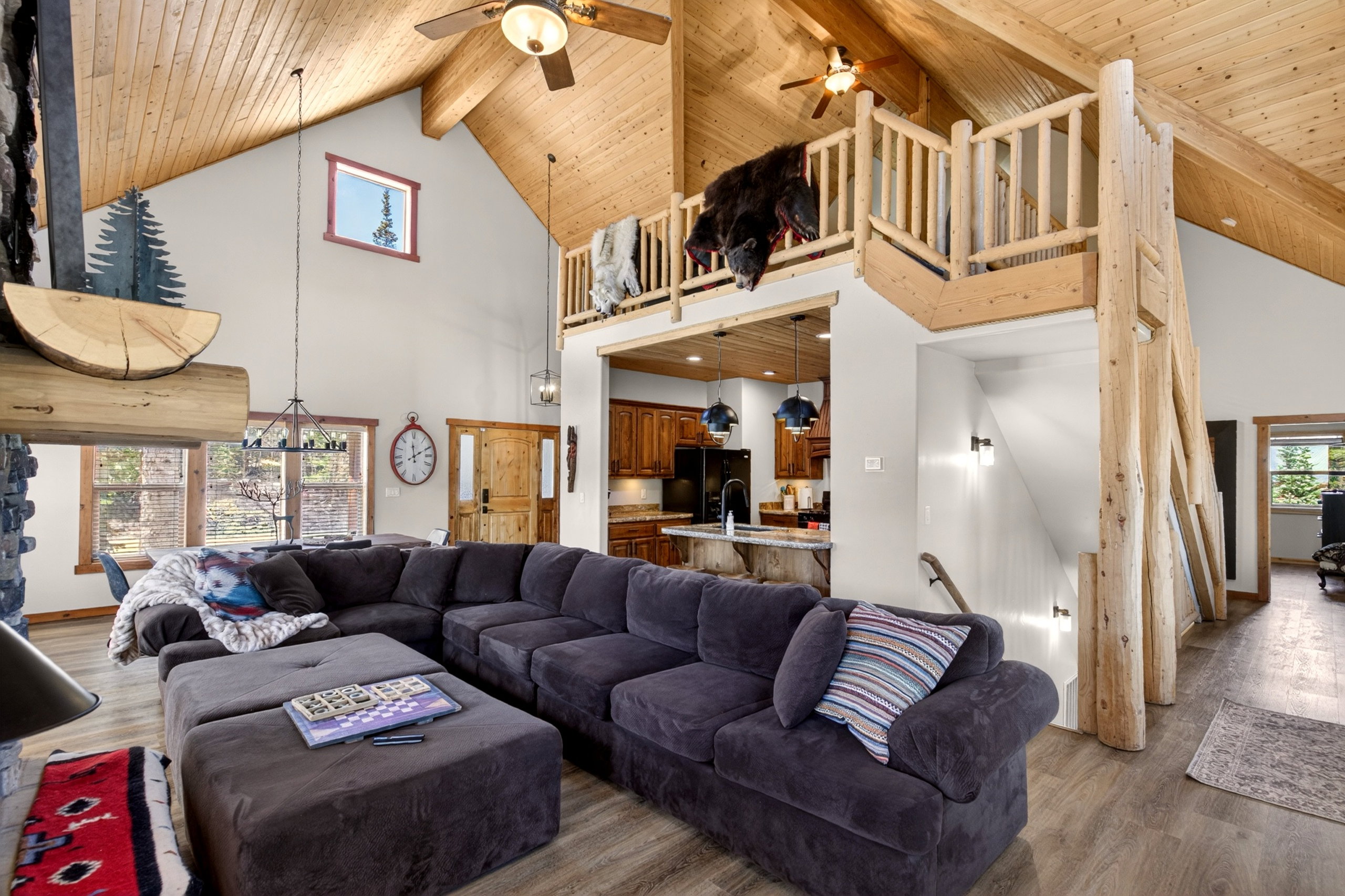 Vaulted wood-paneled ceilings with exposed beams, an open loft area with log railings, and a prominent stone fireplace