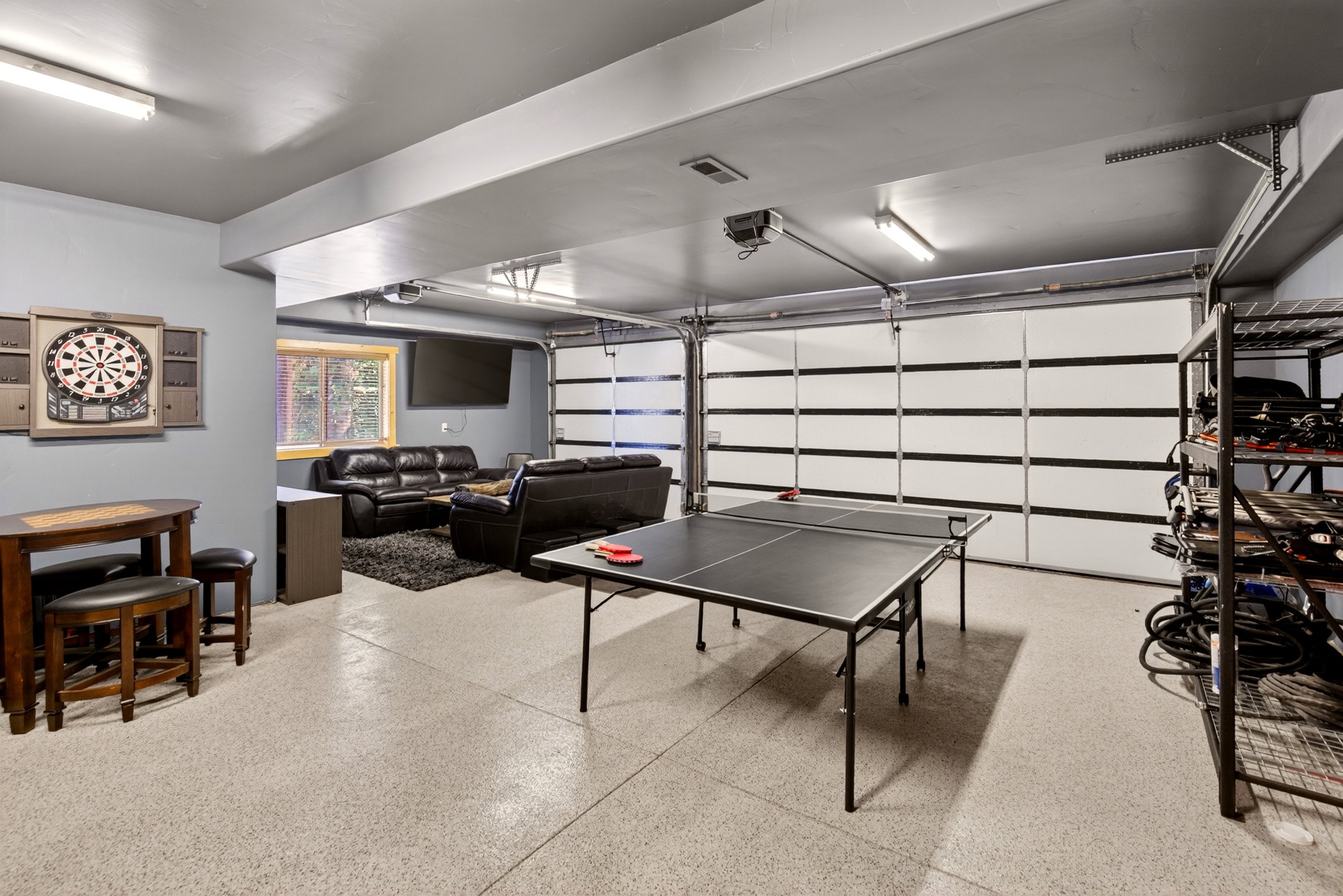 Expansive multi-purpose space featuring epoxy flooring, overhead lighting, and a modern garage door
