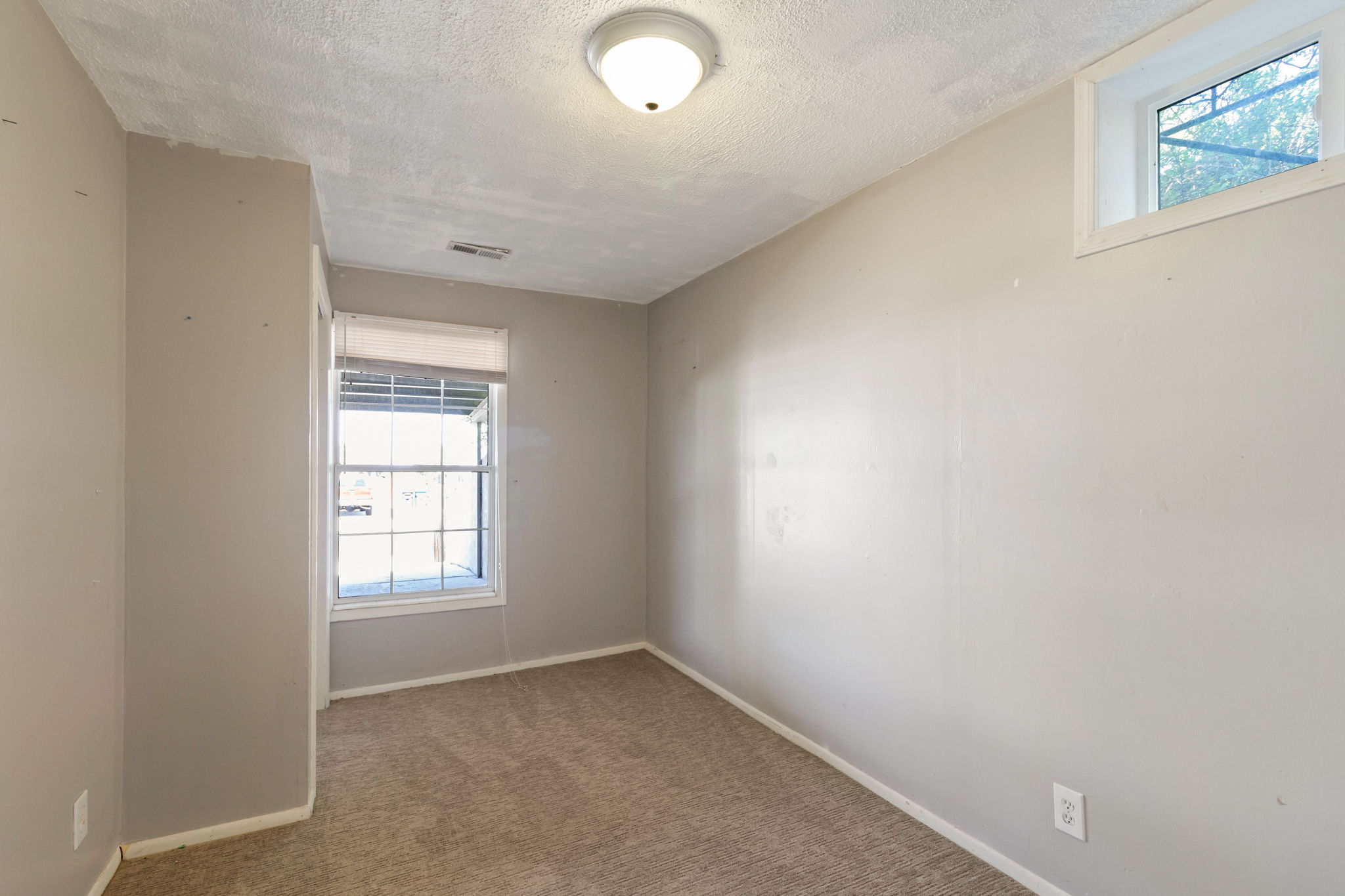 Neutral-toned interior room featuring light gray walls and a textured ceiling