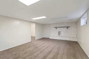 Spacious room featuring a stone-clad fireplace with a mantel, carpeted flooring, white walls, and recessed lighting
