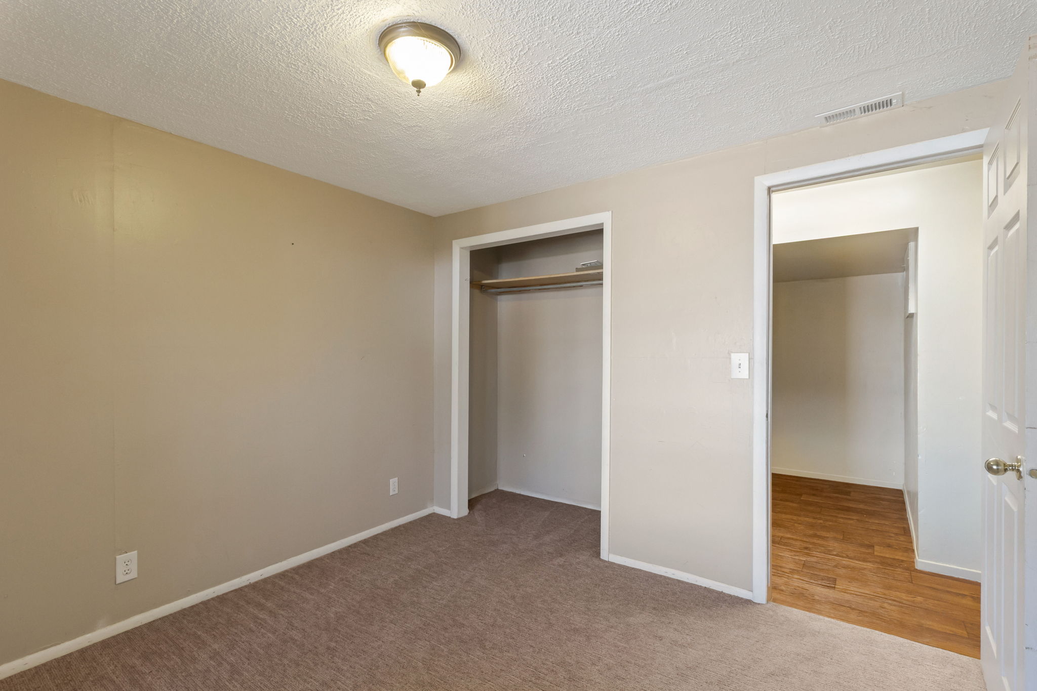 Carpeted room with neutral wall tones and a ceiling-mounted light fixture
