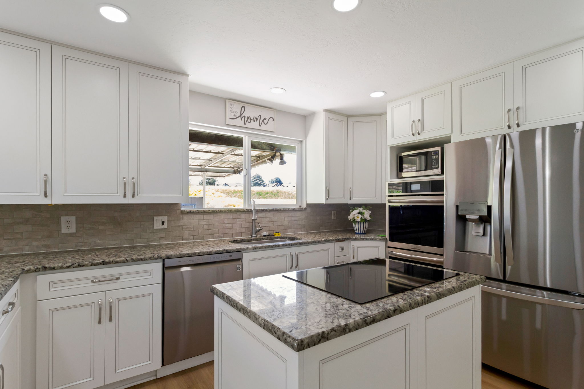 Contemporary kitchen featuring white cabinetry, stone countertops, a mosaic tile backsplash, and recessed lighting