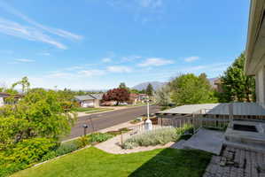 Front entrance with brick paver landing, metal railing, and covered carport