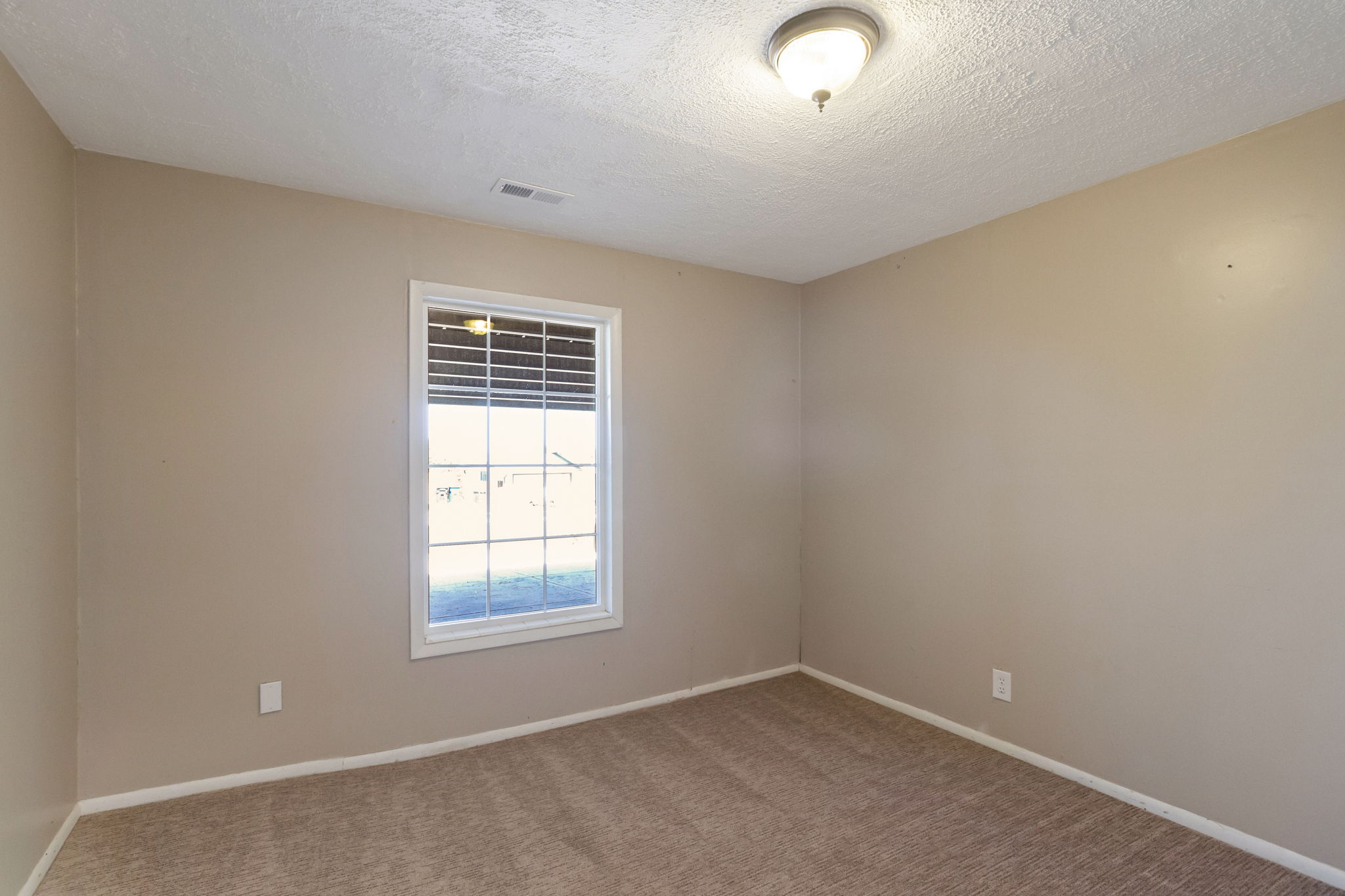Room featuring neutral-toned carpet, a window with horizontal blinds, and a flush-mount ceiling light