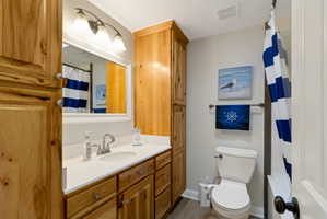 Bathroom featuring a wood-finish vanity with a white countertop and an undermount sink