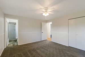 Carpeted room featuring a ceiling fan with light fixture, chair rail molding, and panel doors