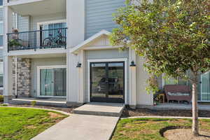 Exterior features include a covered entrance with double glass doors, light gray siding, and stone accent paneling