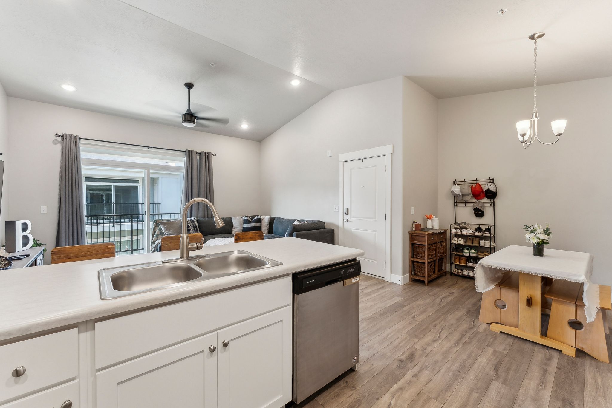 Open-concept living space featuring wood-finish flooring, a kitchen island with a double basin sink and dishwasher, high vaulted ceilings, recessed lighting, and a ceiling fan