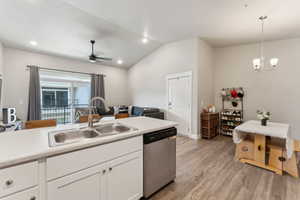 Open-concept living space featuring wood-finish flooring, a kitchen island with a double basin sink and dishwasher, high vaulted ceilings, recessed lighting, and a ceiling fan