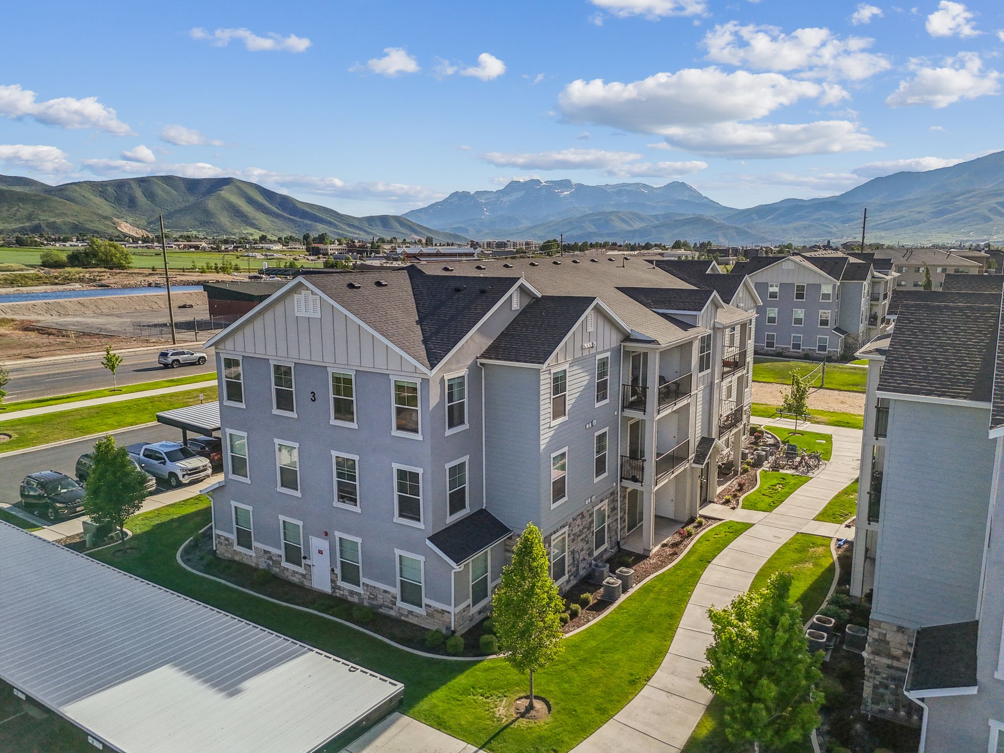 Multi-story residential building featuring light blue siding, stone veneer accents, and multiple private balconies