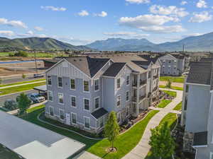 Multi-story residential building featuring light blue siding, stone veneer accents, and multiple private balconies