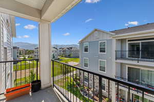Private balcony with black metal railing, offering a clear expanse of blue sky and distant mountains