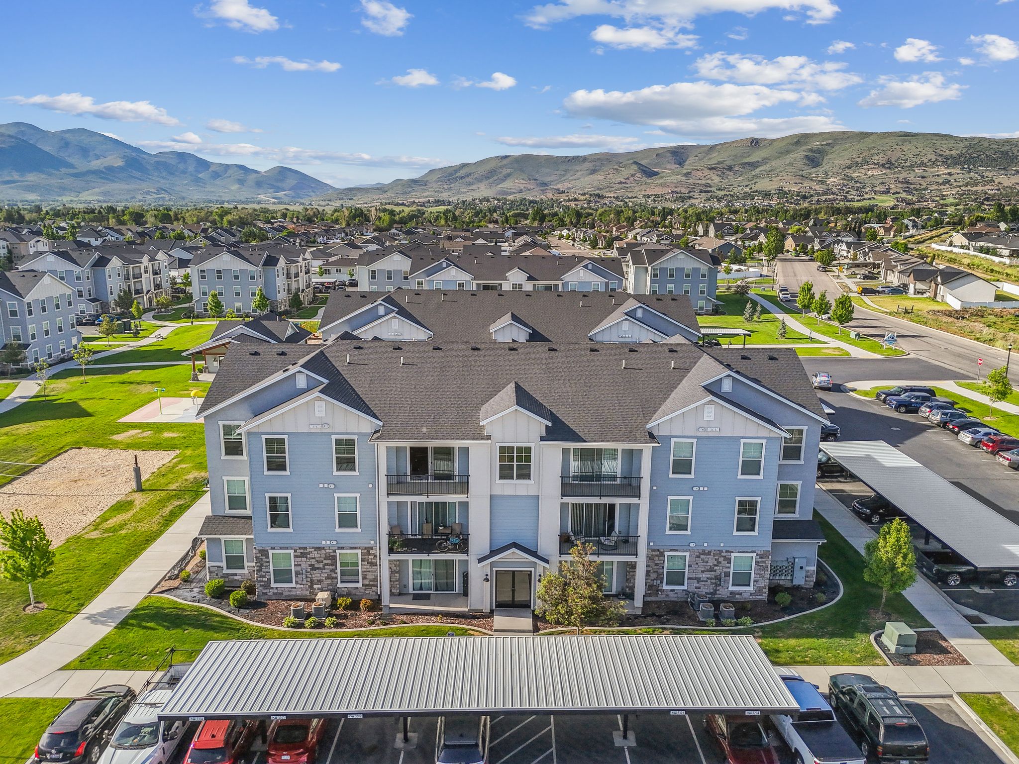 Multi-story residential building with light blue siding, white trim, and stone accents