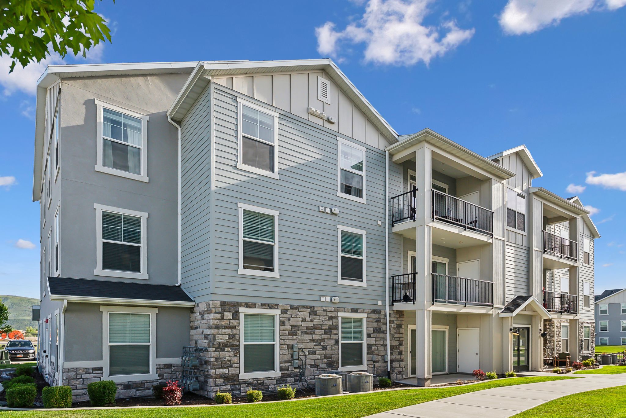 Contemporary multi-story building featuring stucco, horizontal siding, and stone veneer exterior finishes