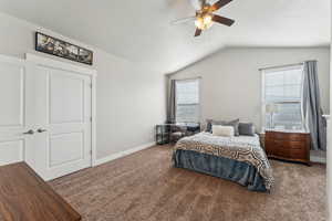 Vaulted ceiling bedroom featuring carpeting, a ceiling fan with integrated lighting, and two windows with blinds
