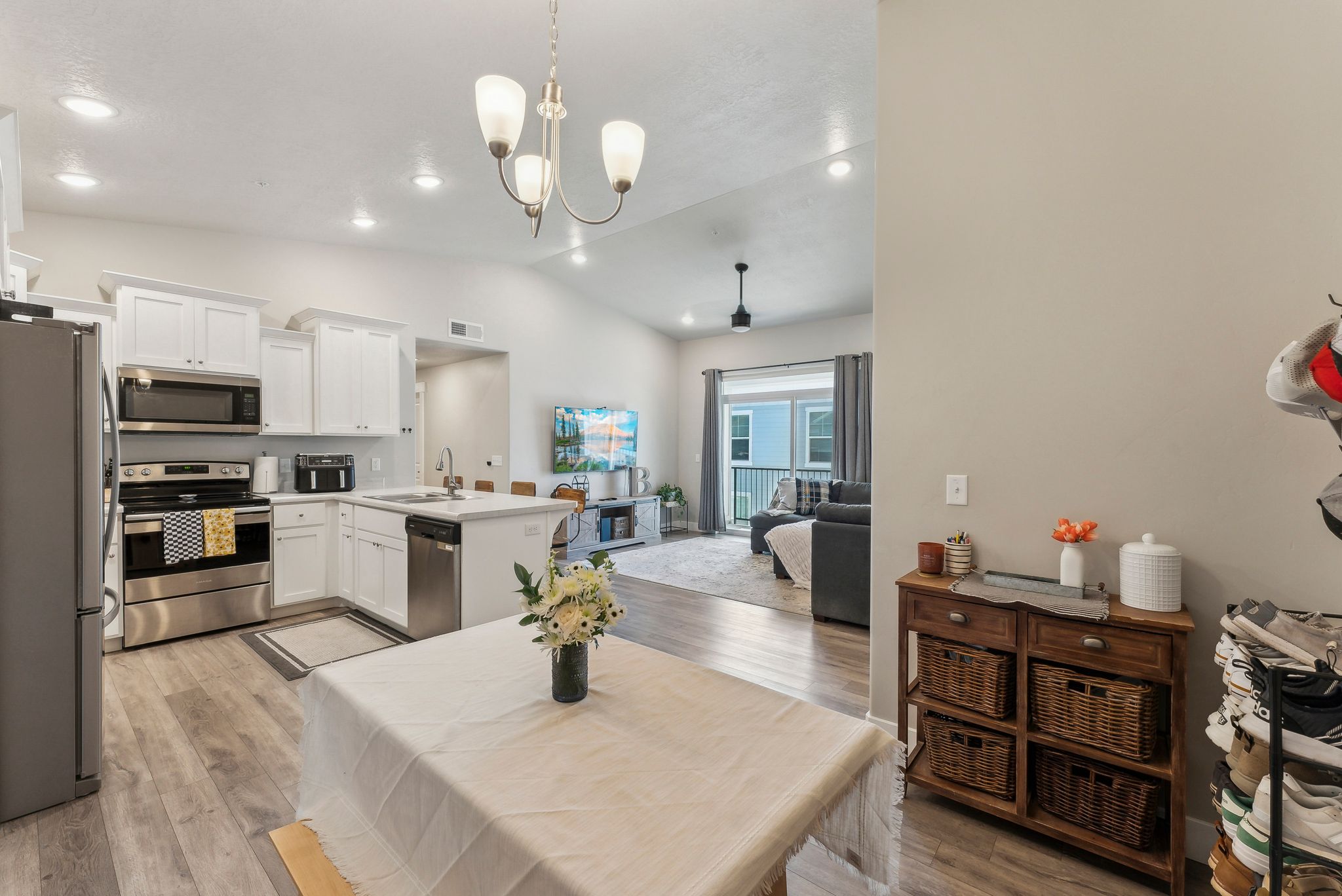 Open-concept living space featuring a kitchen with white cabinetry, stainless steel appliances, and a central island with bar seating