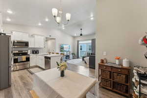 Open-concept living space featuring a kitchen with white cabinetry, stainless steel appliances, and a central island with bar seating