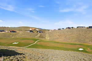 Expansive golf course terrain featuring green fairways, sand traps, and a paved cart path
