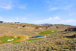 Expansive hillside property featuring a golf course, multiple greens, and a water feature