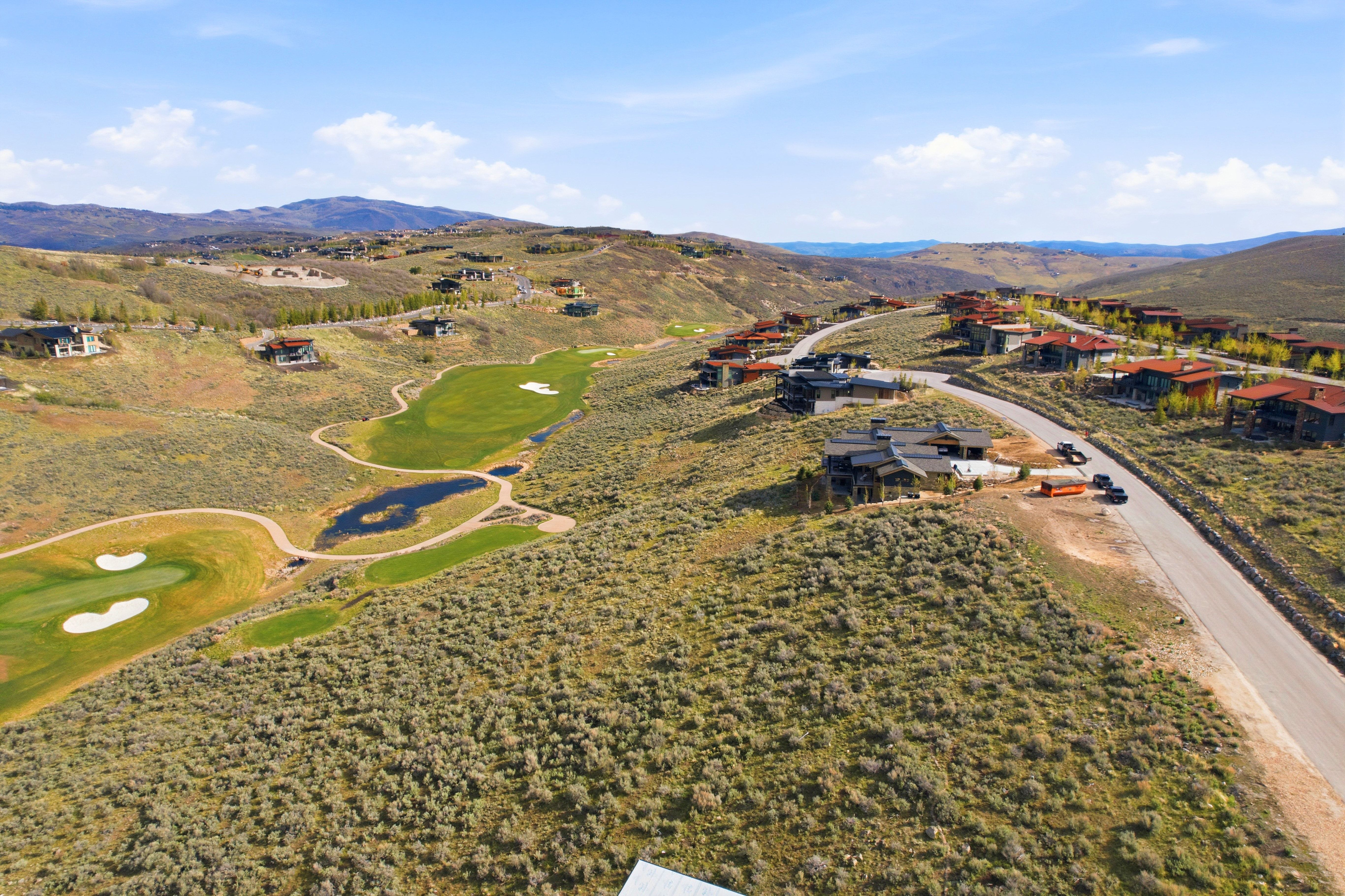 Expansive golf course community featuring multiple fairways, greens, and water features set within a mountainous landscape