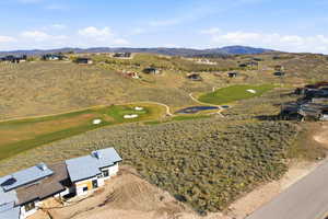 Expansive undeveloped lot featuring natural vegetation, a paved road border, and a building under construction
