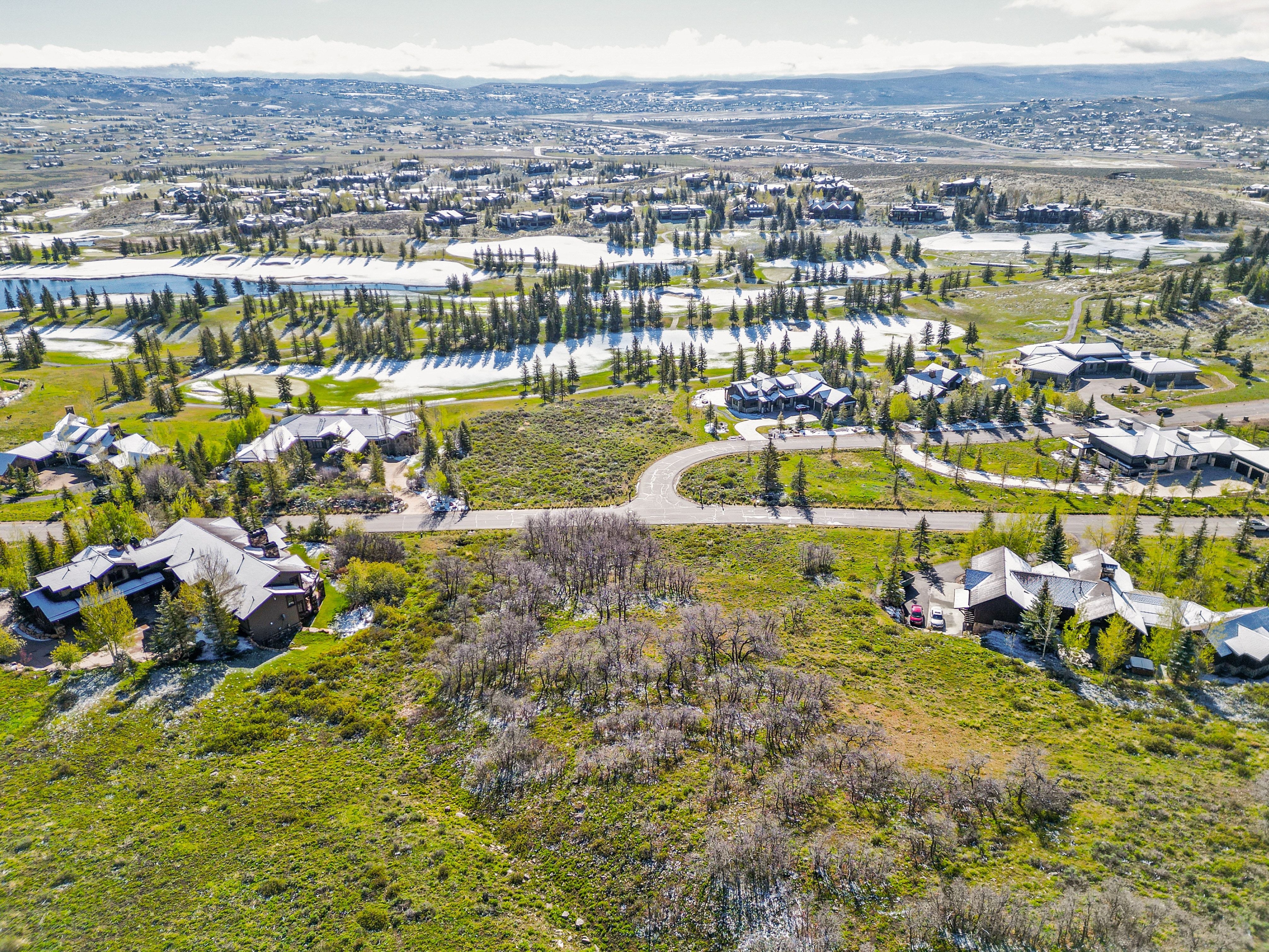Expansive undeveloped land parcel surrounded by established residences and natural landscapes