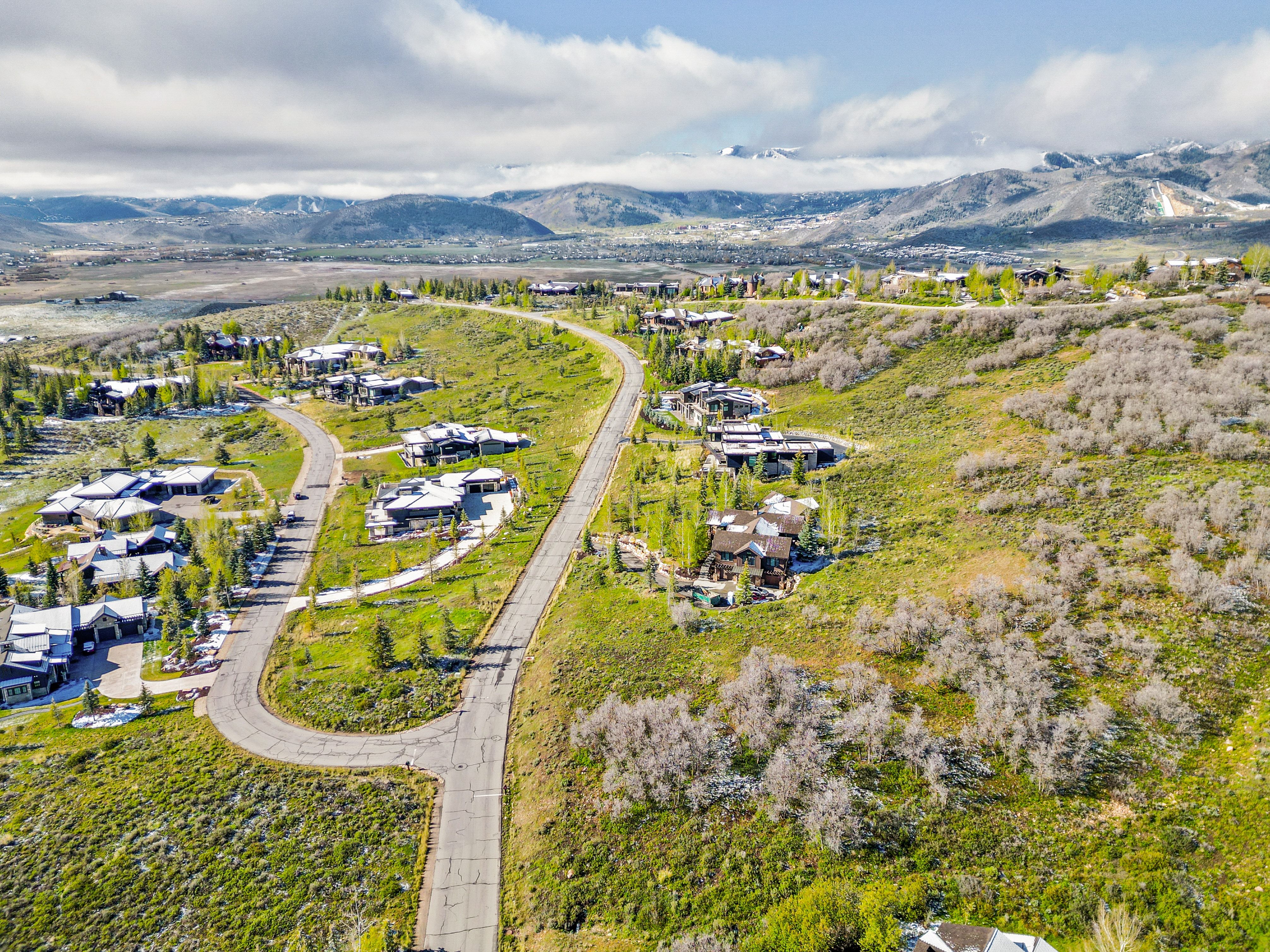 Spacious hillside properties featuring a winding paved road and expansive natural landscaping