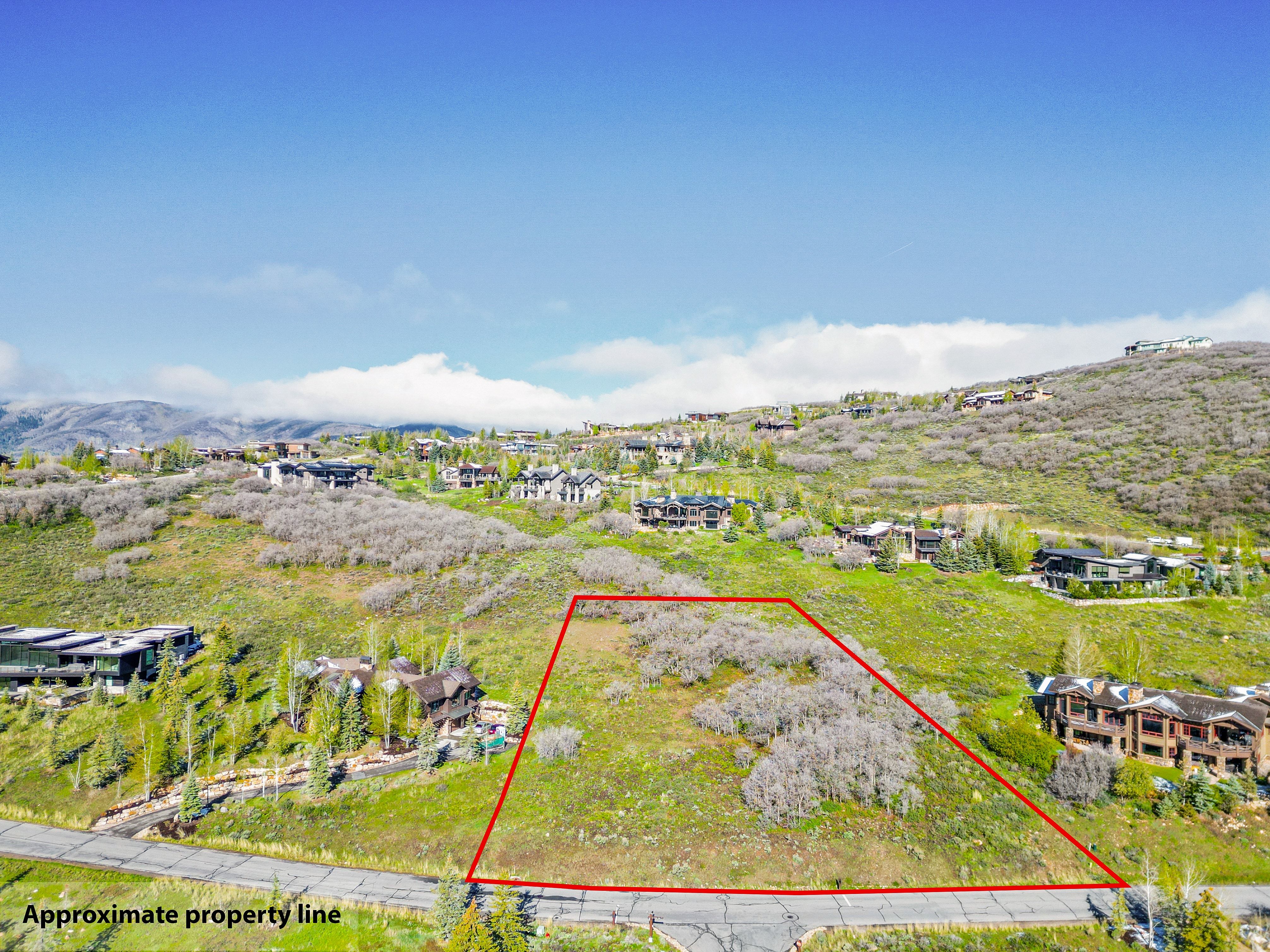 Elevated lot featuring a verdant hillside, surrounding residential properties, and distant mountain ranges