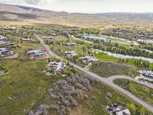 Expansive aerial depiction of a residential area featuring a golf course with water features, surrounding green spaces, and mountain backdrop