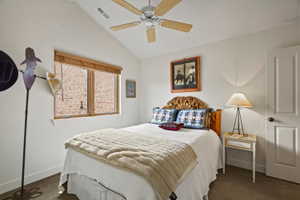 Vaulted ceiling bedroom with a wood-finish ceiling fan and two-panel interior door