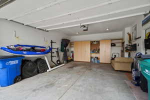 Spacious garage featuring concrete flooring, built-in cabinetry, recessed lighting, and an automatic garage door opener