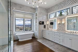 Freestanding pedestal bathtub beneath a large window with mountain scenery