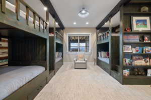Built-in bunk beds with integrated storage drawers, exposed ceiling beams, recessed lighting, and a neutral-toned window